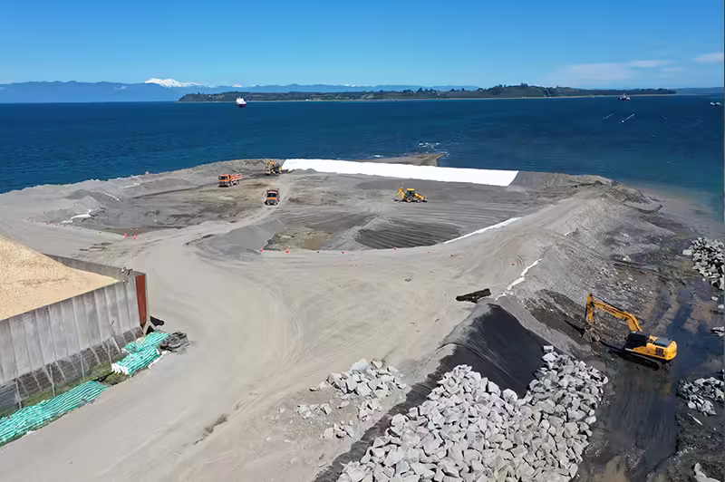 Obras de ampliación en el Puerto Punta Caullahuapi en Puerto Montt, con maquinaria pesada trabajando cerca del mar.