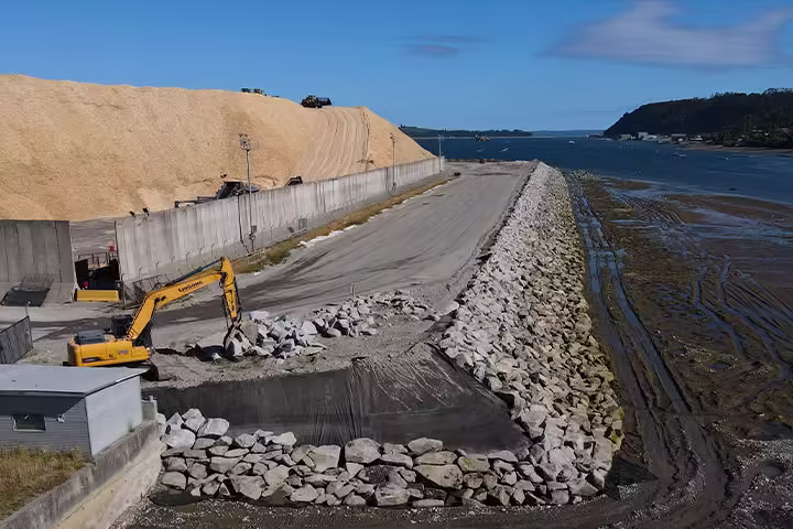 Excavadora trabajando en la construcción de enrocado en la ampliación del puerto en Puerto Montt.
