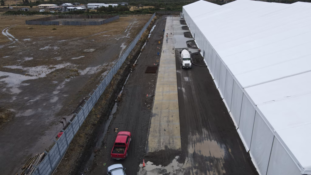 Imagen del avance de pavimentación en el área lateral del Proyecto Vitra, con camiones y vehículos en el sitio de construcción.