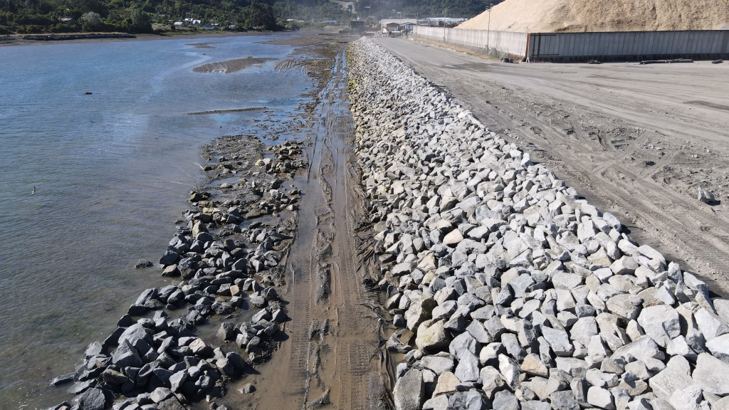 Vista del enrocado de protección costera terminado en la ampliación del Puerto Punta Caullahuapi, mostrando la separación entre el mar y la nueva área del puerto.